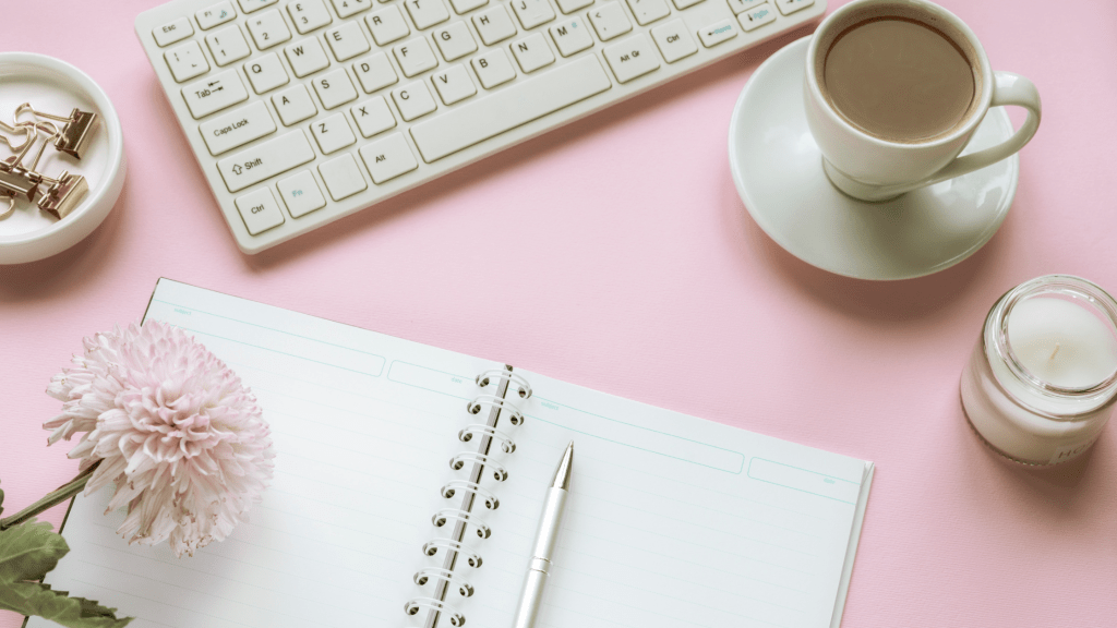 Carnet d’écriture ouvert sur un bureau pastel, avec un café et un clavier, symbole de créativité littéraire selon Cécile Debray.